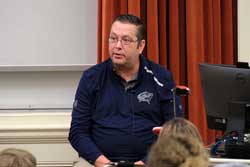 TJ LaMendola speaks at a  podium
