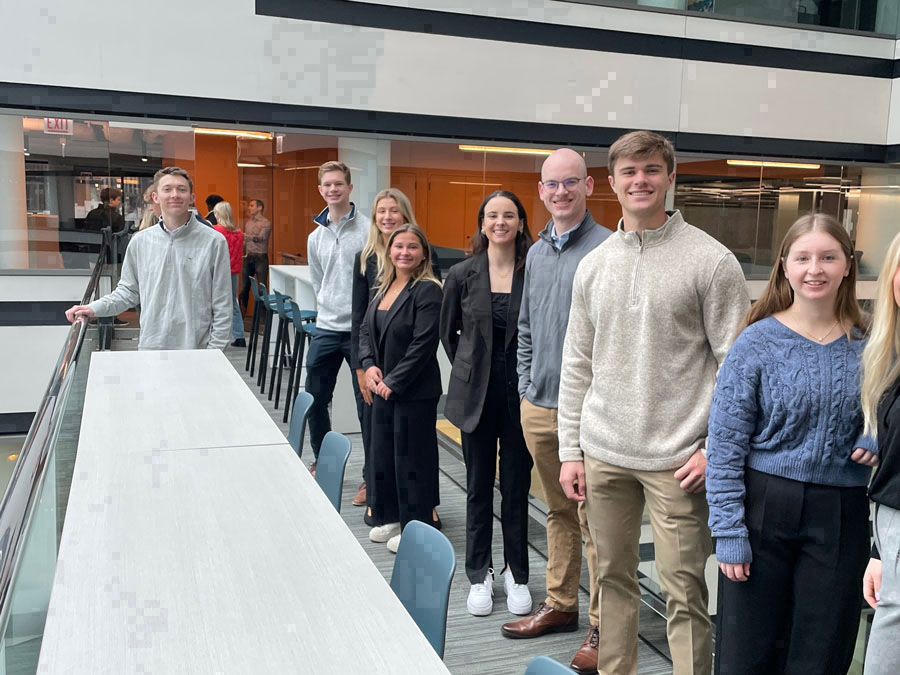 A group of students standing behind a long conference table