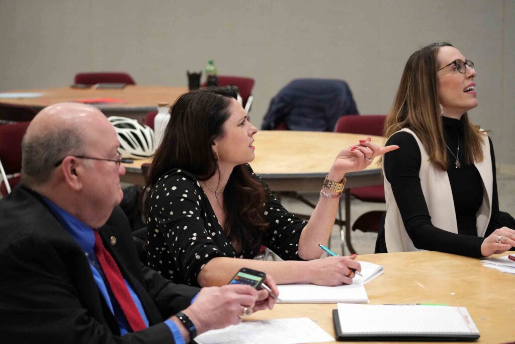 Photo of three judges seated at a round table, asking questions.