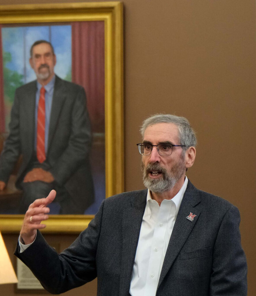 A photo of Marc Rubin with his portrait in the background