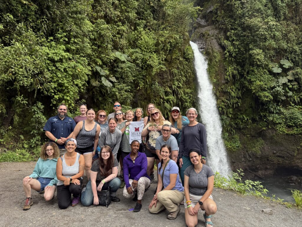 Students smiling in front of a waterfall