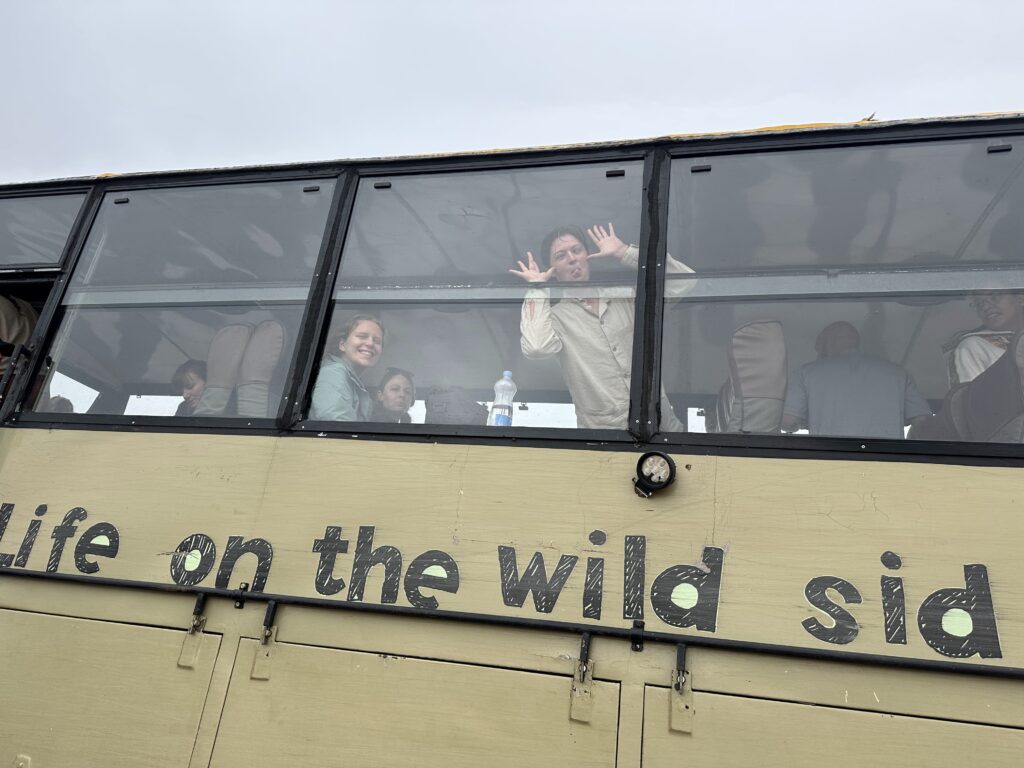 Students having fun on a bus with the letters "Life on the wild side" on the side of it.