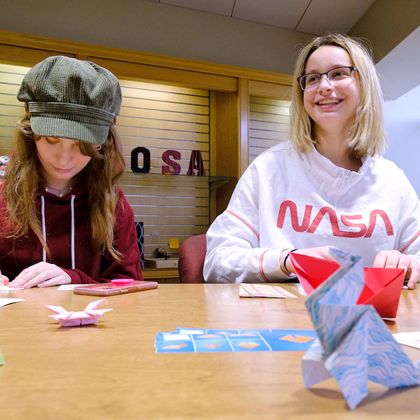 Two students creating origami crafts