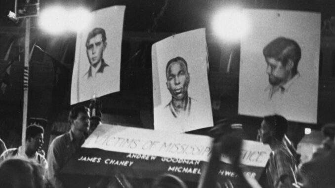 A photo taken by photographer Bob Fletcher of a Freedom Summer event where participants were holding up pictures of the three Freedom Summer volunteers who were murdered by the KKK.