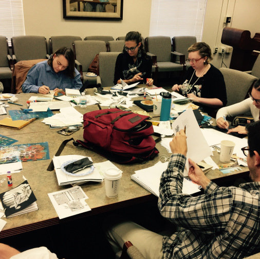Photograph of Miami MFA students making collaged books at a table covered with scraps of paper and partially finished books.