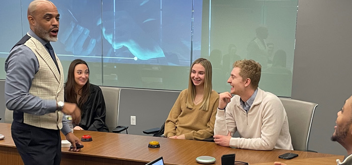 Photo of students at a table conversing with a businessman.