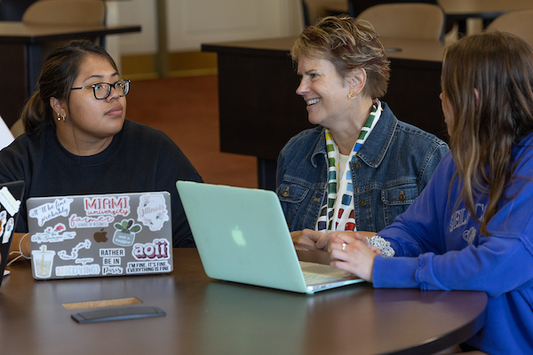 Two students converse with accounting faculty