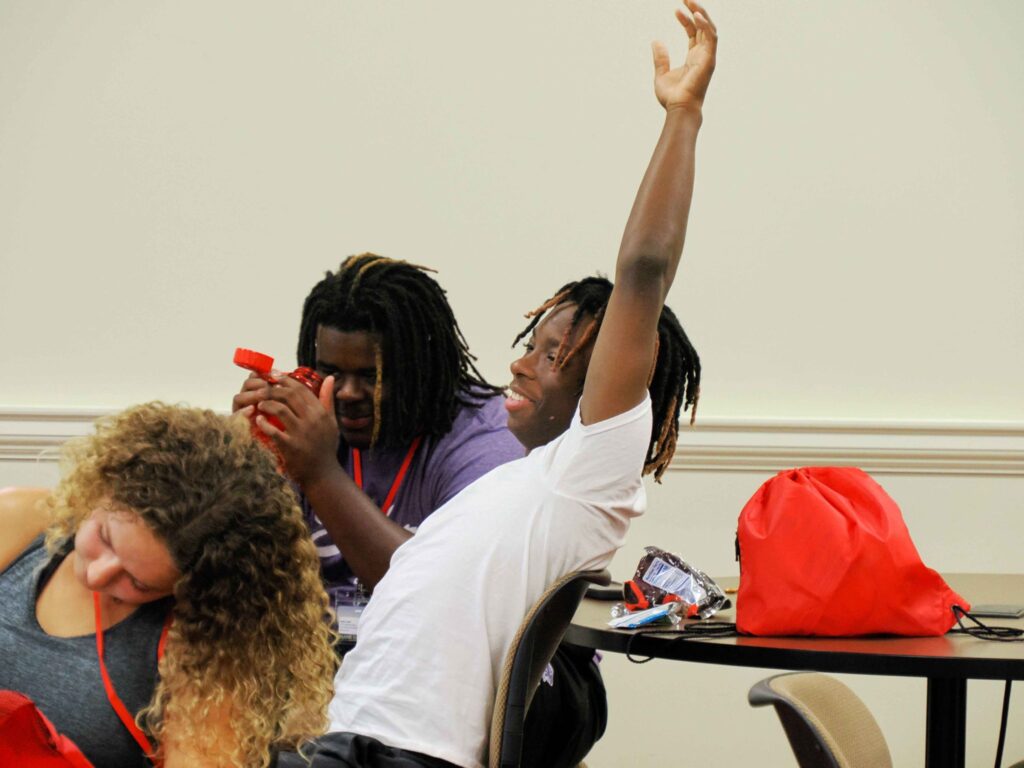 close-up of a student raising his hand to answer a question