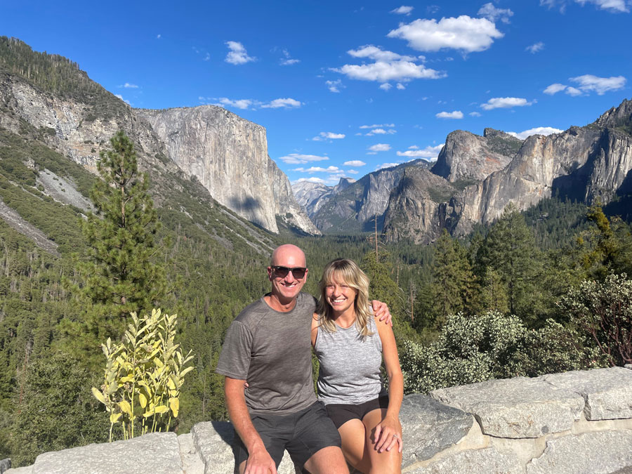 Photo of Kyle Bikhart and his wife Adrienne Keves against a scenic view of mountainous cliffs