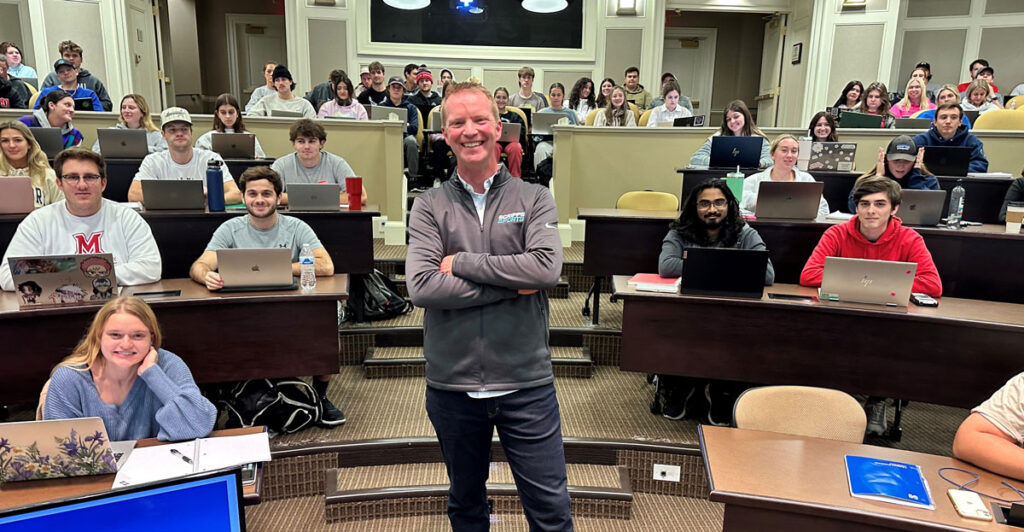 Dan Perschke of E.W. Scripps poses in front of a group of students in a lecture hall.