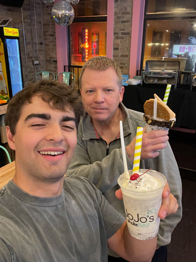 Two men holding up milkshakes