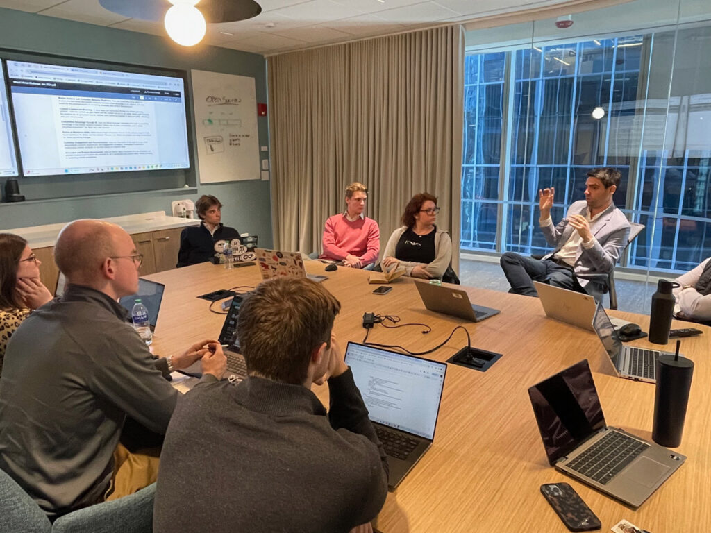 A group of students and professionals actively discussing at a conference table