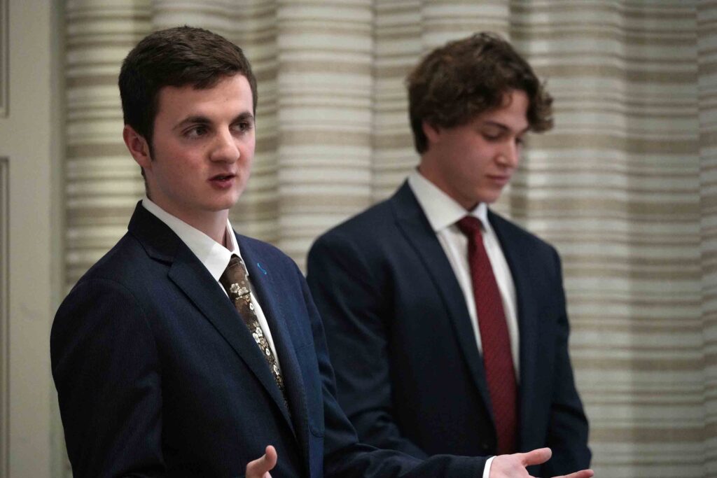 Close-up photo of two male students in business attire presenting