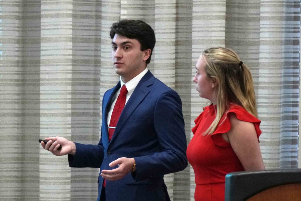 Photo of a male and a female student in business attire presenting 