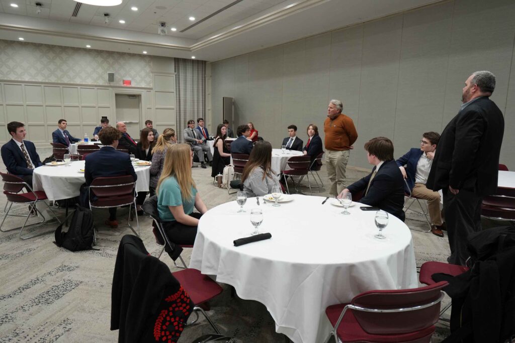 Photo of participants in round tables listening to sponsor Mike Millett speak