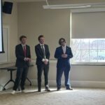 Photo shows a presenting team receiving feedback from a panel of judges