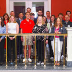 Group photo of 38 attendees consisting of faculty, AAG members, and students on the FSB balcony