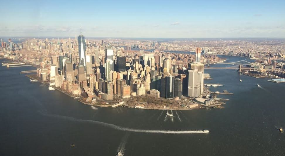 A view of the southern tip of Manhattan, showing the dense cluster of skyscrapers in the Financial District surrounded on three sides by the waters of New York Harbor.