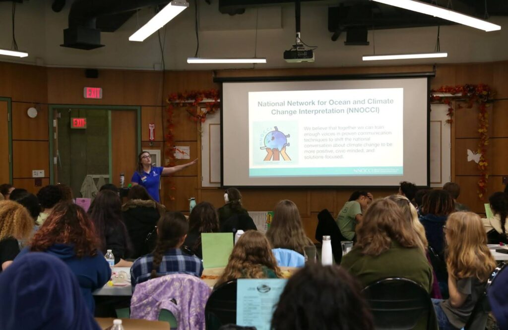 Kait Birghenthal giving a slide presentation to an engaged audience of students at the Rhode Island Youth Climate Conference.