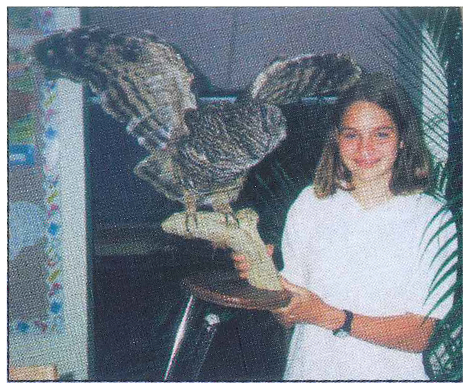 A young girl, Ashley Pickard, holding up a taxidermy owl.