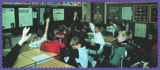 A class of students raising their hands.