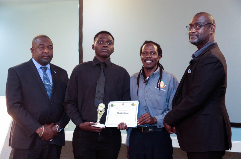 Proud young adult graduates in professional attire holding certificates and awards alongside program facilitators at a formal indoor event.