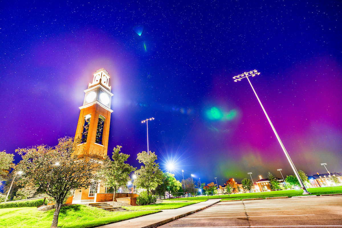 Miami's Oxford campus highlighted by an aurora in the sky. The lights on campus are very bright from the long camera exposure.