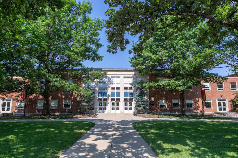 The exterior of Philips Hall on Miami University's Oxford Ohio campus surrounded by leafy green trees in the summer.