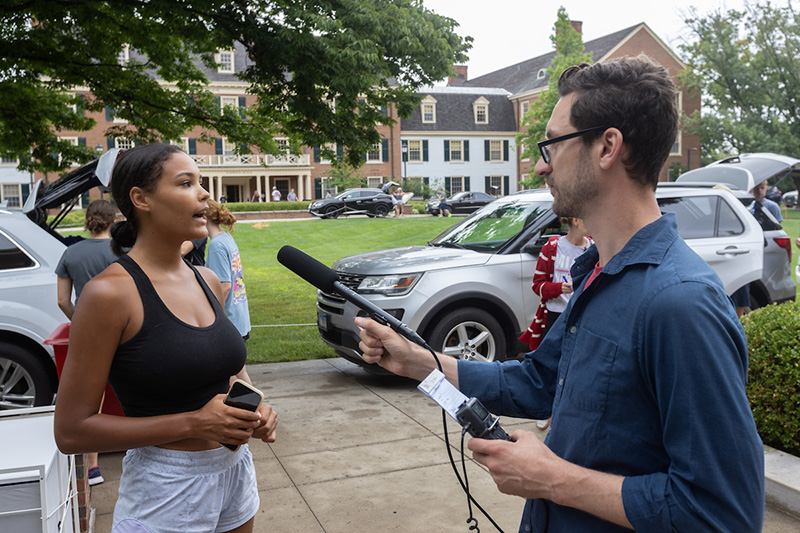 a news team member interviewing a student on campus