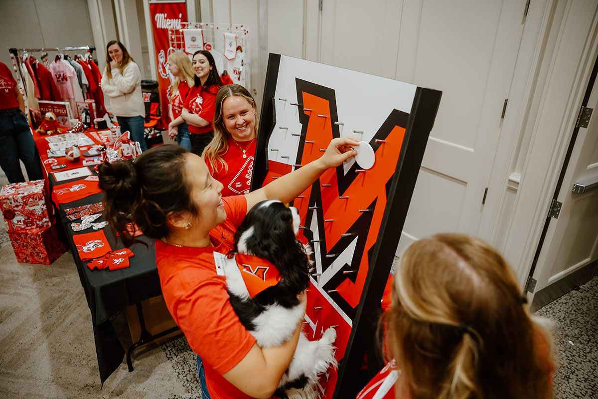 Brand camp volunteers host a merchandise table and plinko board
