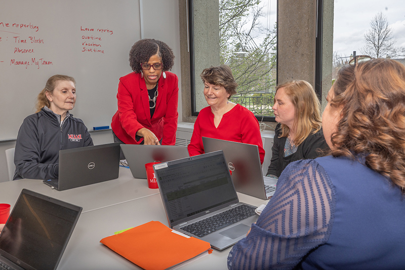 a group of Miami employees sitting around a computer working together