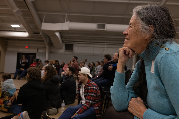 woman with her fist under her chin watching a group perform