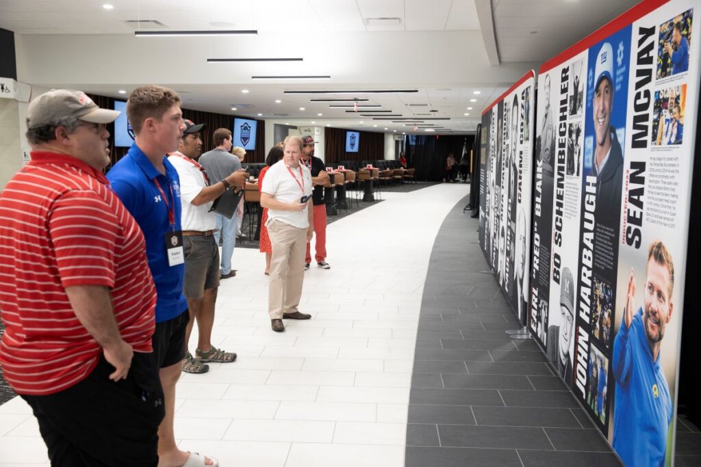 Large banners display the photos and names of Miami football coaches including Weeb Ewbank, John Pont, Ara Parseghian, Carm Cozza, Early Blank, Bo Schembechler, and Sean McVay.