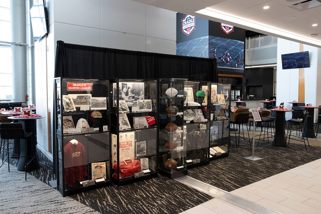 Display cases of football artifacts curated by Miami University Libraries for the Cradle of Coaches documentary pre-release party