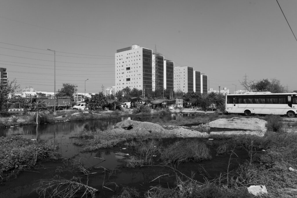 swampy abandoned parking lot with a power lines and buildings in the background