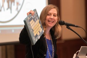 Janet Peters holding up an accessible keyboard at the 2017 Accessible Technology Symposium
