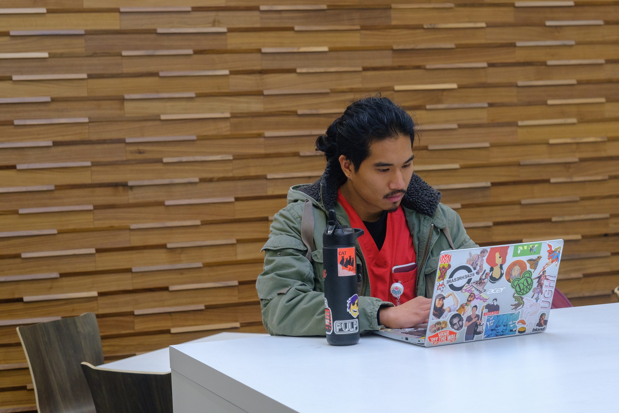 A student sits at a table with a laptop.