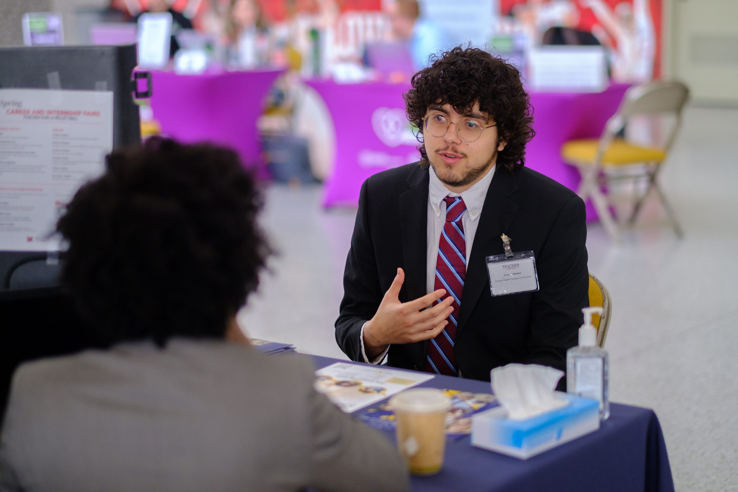 Man in business attire interviews with employer. Having a good LinkedIn summary can help job seekers be seen by more potential employers.