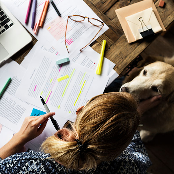 A women highlighting her study notes with her dog close by