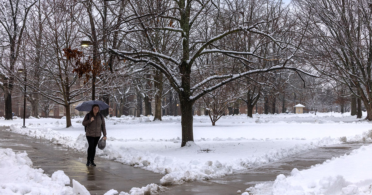 A student walking on a snowy path on a cold day