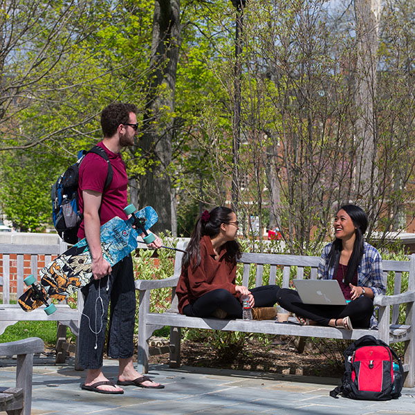 Three college students gathered outside discussing AI technology tools.