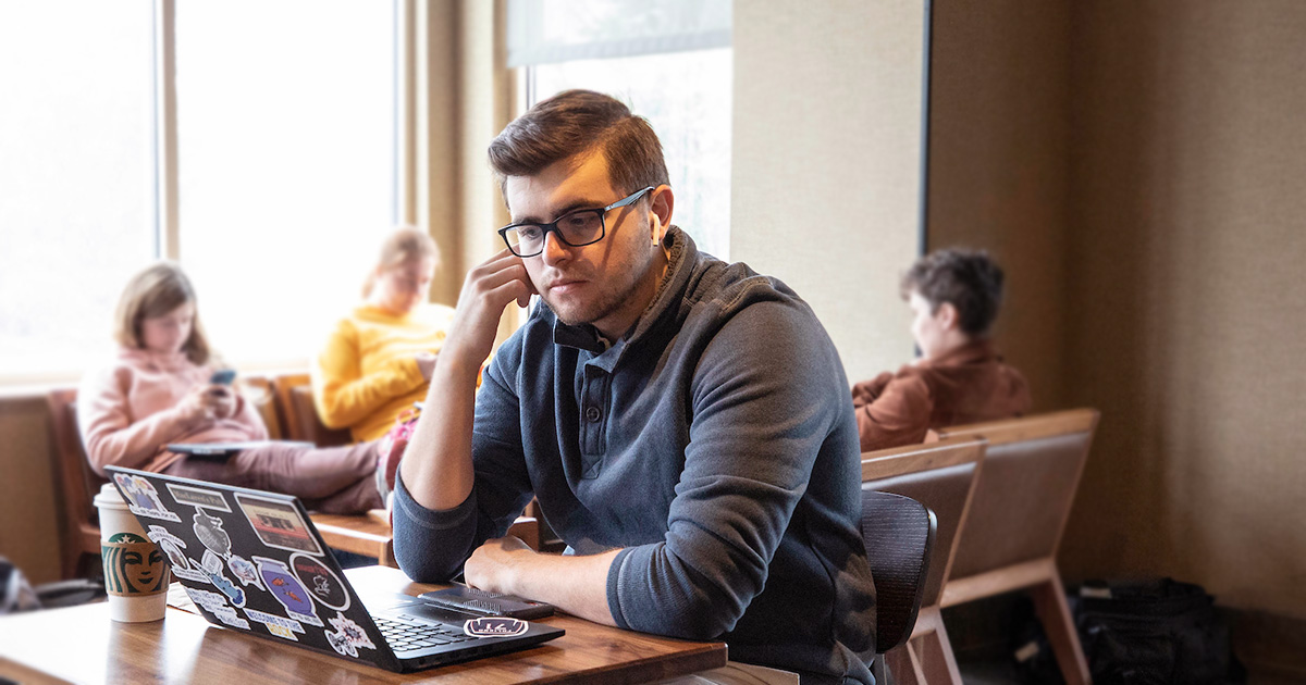 An online student working on a laptop computer at a coffeeshop