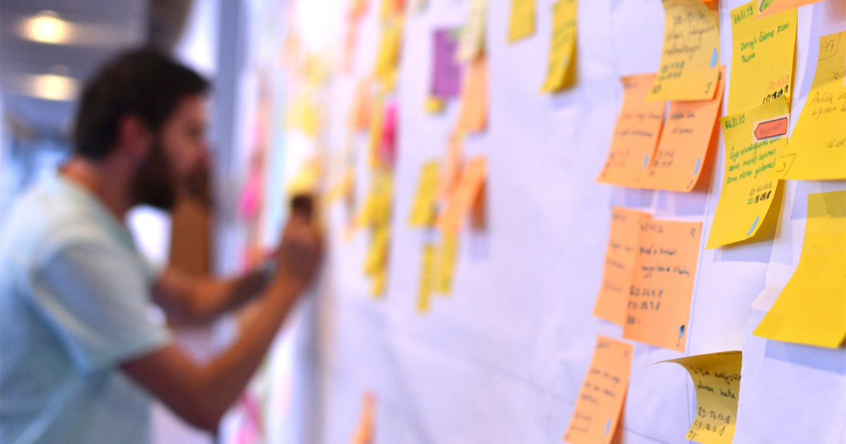 A man learning Agile project management concepts by organizing sticky notes on a board.