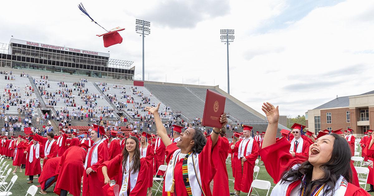 Miami University graduates excitedly tossing their graduation caps into into the air