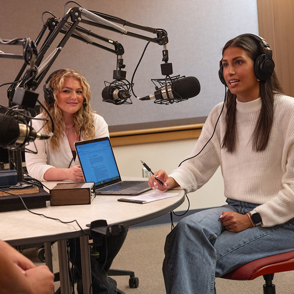 Two women in a Miami University sound studio recording a podcast about improving writing process.