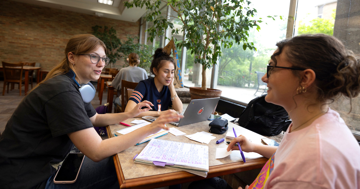 Three Miami University students studying together with their books and laptops
