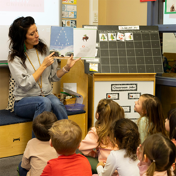 A pre-K teacher reading a storybook to her class.