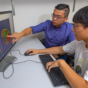 A faculty member giving feedback to a student working with computer-aided drafting software