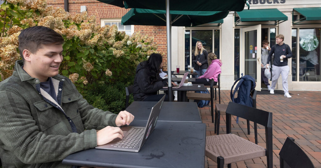 A student working on his Leadership Essentials course at a coffee shop.