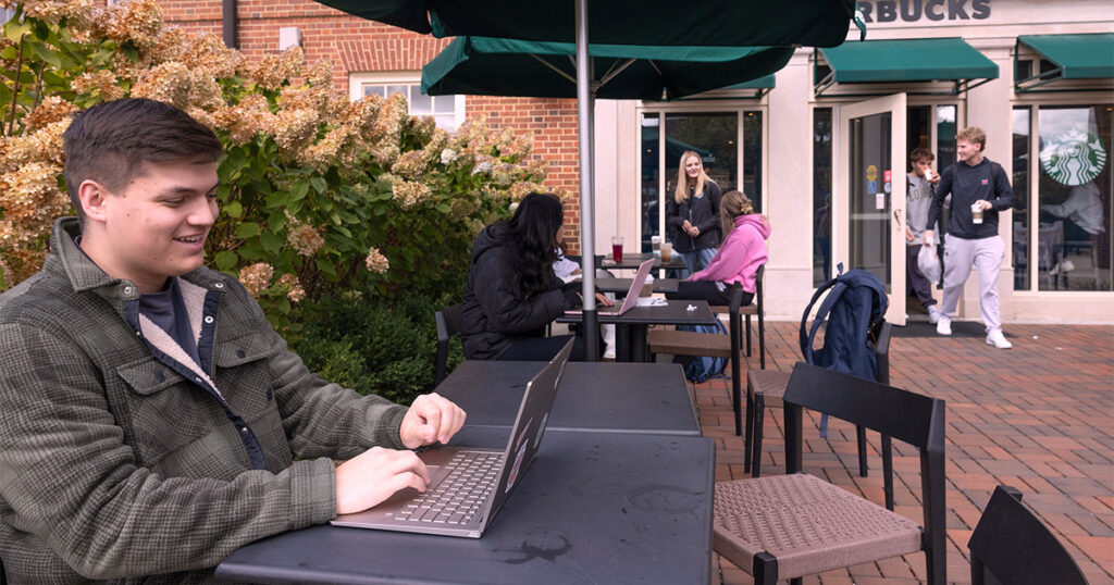 A student studying outside of a coffee shop with his computer